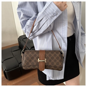 Detail view of a vintage pattern baguette bag with a gold buckle worn as an underarm bag