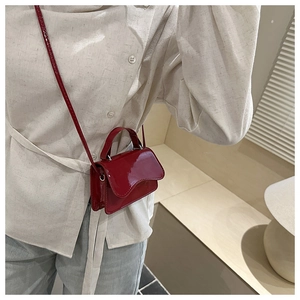 Detailed side view of a red patent leather mini crossbody bag on a model