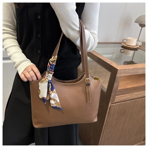 Brown faux leather tote bag detail featuring white stitching and decorative silk scarf