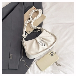 Detail of off-white pleated handbag with pearl chain, floral accents and metal logo patch