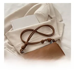 Close-up of brown matte crossbody bag featuring a unique knotted shoulder strap design
