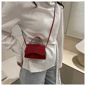 Detail of red patent leather mini bag with wavy flap and silver hardware details