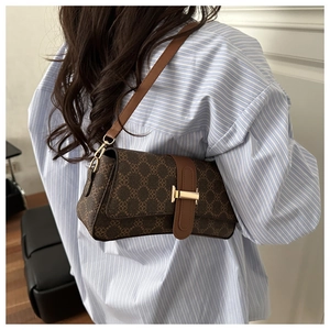 Detailed close-up of textured monogram canvas and T-shaped metal clasp on shoulder bag