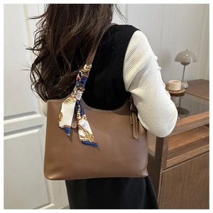 Brown leather tote bag detail with decorative floral silk scarf on shoulder strap
