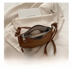 Detail view of brown crescent shoulder bag interior with phone and cosmetics