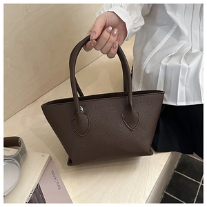 Detail of a brown lychee pattern leather tote bag with heart-shaped reinforced stitching