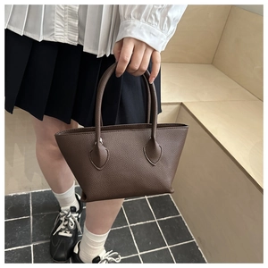 Close-up of a dark brown lychee leather bucket bag with stitched leaf-shaped handle details