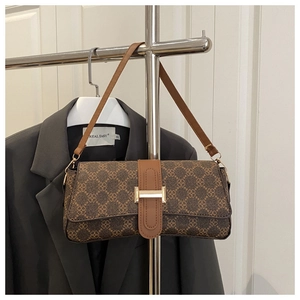 Detail of vintage patterned baguette bag with brown leather strap and metal buckle