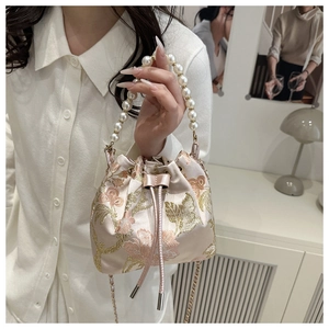 Close-up of silk bucket bag showing pink floral embroidery and pearl handle detail