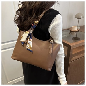 Detail of brown pebbled leather tote bag with elegant silk scarf on the shoulder strap