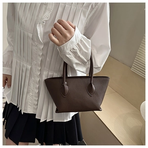Close-up of dark brown lychee-pattern leather tote bag with cylindrical handles