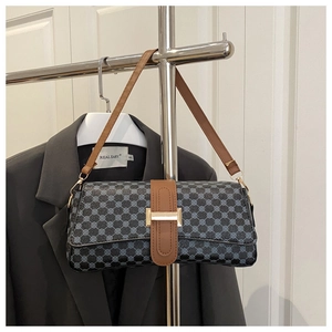 Detail of blue geometric patterned baguette bag with brown leather strap and gold clasp