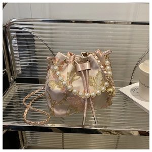Detailed embroidery on pink satin bucket bag with pearl handle and metal strap