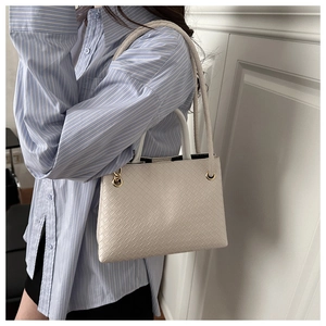 Detailed view of the intricate woven leather texture and gold hardware of the cream tote bag
