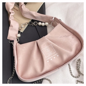 Detail of pink pleated satin handbag featuring pearl flower chain and branding
