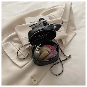 Detail of girls' black quilted mini bucket bag with silk scarf bow and gold chain strap