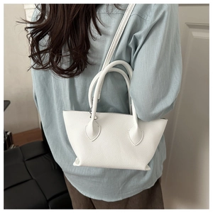Rear view of a white lychee grain bucket bag worn crossbody with casual attire