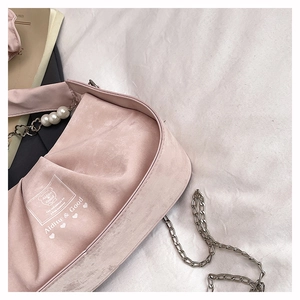 Close-up of pink pleated suede handbag with pearl charms and silver chain detail