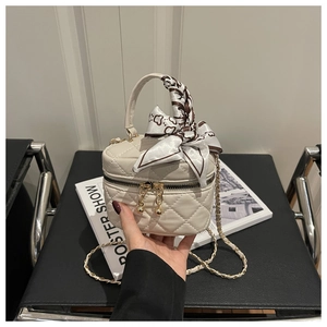 Detail of cream quilted mini bucket bag with scarf handle and gold chain strap
