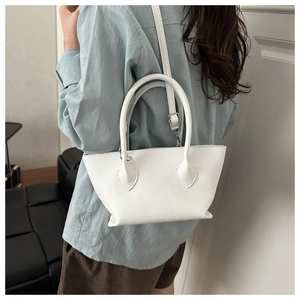 Detailed close-up of white lychee pattern leather handbag with adjustable crossbody strap