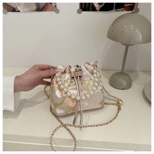 Close-up of floral embroidery, pearl handle, and drawstring on a pink bucket bag