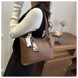 Brown tote bag detail featuring an elegant blue silk scarf and adjustable metal strap buckle