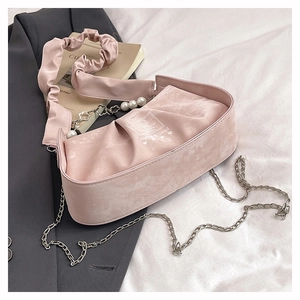 Detail of pink pleated handbag with pearl chain strap and brand logo on fabric