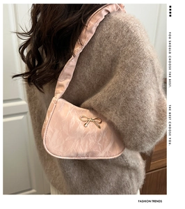 Gros plan sur le sac porté épaule rose plissé avec nœud doré et bandoulière en satin