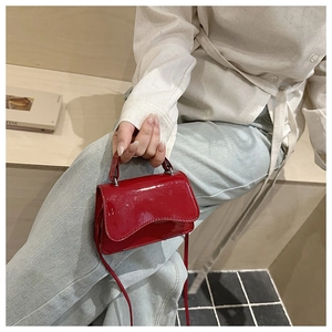 Close-up of a red patent leather mini handbag styled with beige shirt and blue jeans
