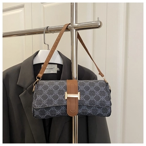Detail of navy patterned shoulder bag with brown leather trim and gold magnetic closure