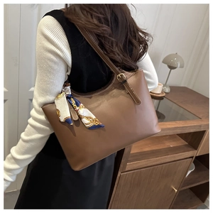 Detail of dark brown leather tote bag with printed silk scarf on adjustable shoulder strap