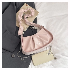 Detailed shot of pink pleated shoulder bag with pearl handle and metal chain decoration