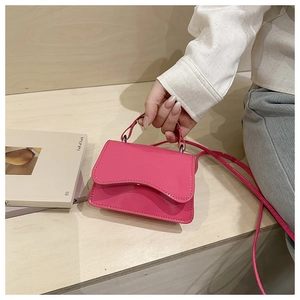 Detailed shot of a magenta glossy mini square handbag with top handle and slim strap