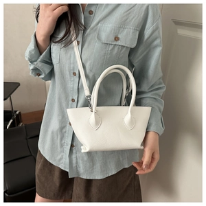 White bucket bag with lychee texture shown on a model with dual handles and strap