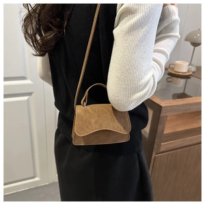 Detail of a brown vintage crossbody bag with soft matte texture and leather handle