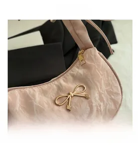 Gros plan du sac croissant rose à motif marbre avec nœud doré et texture plissée