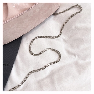 Close-up of pink suede pleated bag with silver chain and white heart logo detail