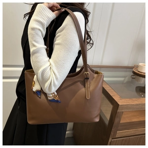 Brown tote bag with white contrast stitching and a silk scarf on the handle