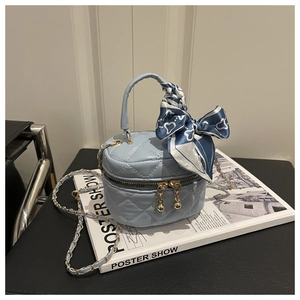 Close-up of light blue quilted bucket bag with chain strap and silk scarf detail