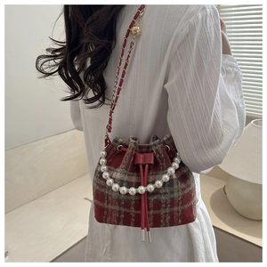 Detail view of red plaid bucket bag with pearl handle and metal chain shoulder strap