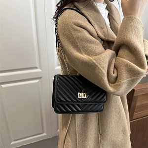 Classic black quilted leather crossbody bag with gold chain strap shown on model