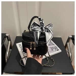 Detail of black quilted mini bucket bag with silk scarf handle and gold chain strap