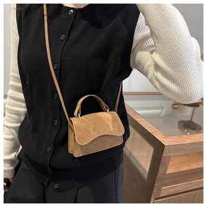 Close-up of a brown suede crossbody bag showing textured fabric and shoulder strap detail