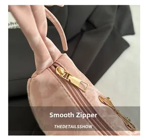 Détail d'un sac à main rose montrant une fermeture éclair dorée et un nœud en métal chic