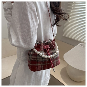 Detail of red-brown checkered bucket bag with large pearl handle and metal chain strap