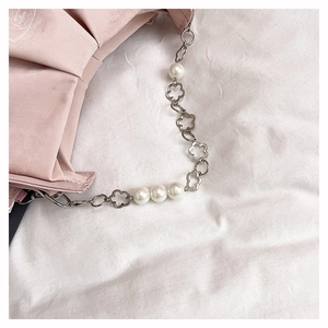 Detail of pink fabric bag with ornate floral metal chain and large white pearls
