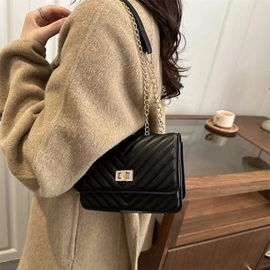 Chic black crossbody bag with chevron stitching and gold chain strap on a model
