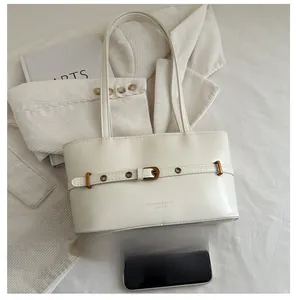 Detail of cream leather tote bag featuring decorative belt strap and gold buckle