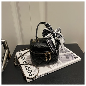 Detail of black quilted mini bucket bag with silk scarf handle and gold chain strap