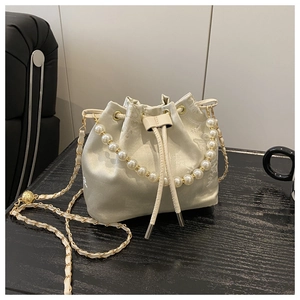 Detail of champagne satin bucket bag featuring floral embroidery and pearl chain handle